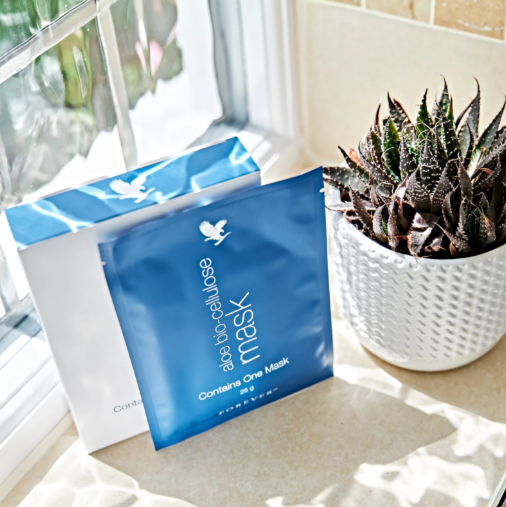 Sachet de masque Aloe Bio-Cellulose Forever posé près d'un plant d'aloe vera, sur un rebord de fenêtre lumineux