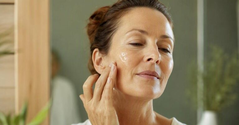 Femme appliquant de l'aloe vera pour peau déshydratée sur sa joue, dans sa salle de bain