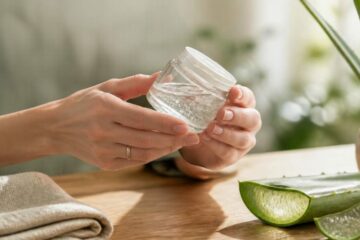 Mains tenant un pot de gel d'aloe vera transparent pour vérifier sa qualité, à côté d'une feuille d'aloe vera fraîchement coupée